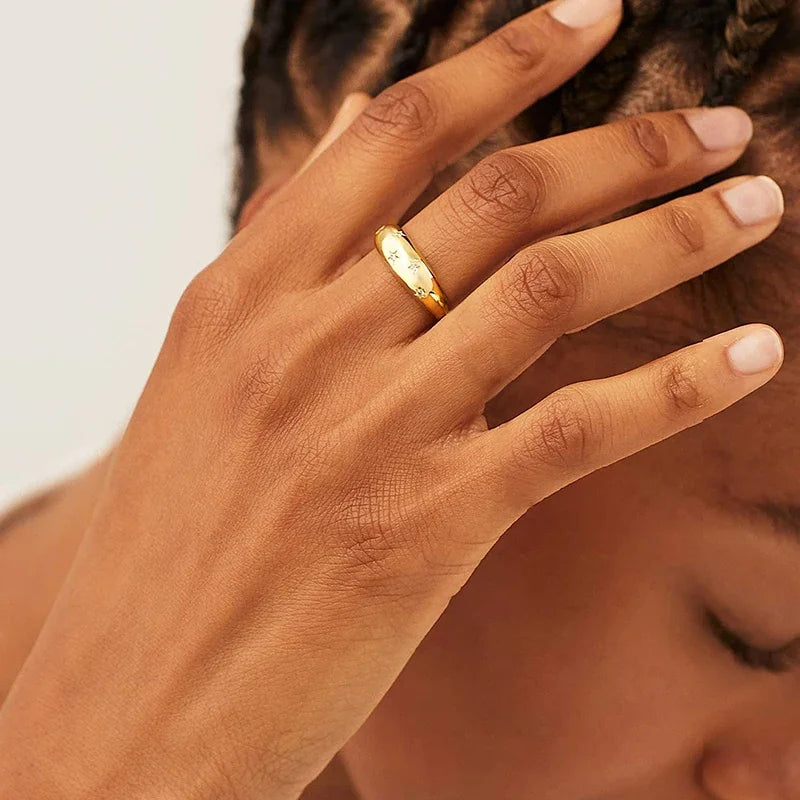 Gold-tone star wedding band on finger, hand pose close-up