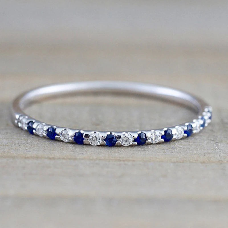 Silver ring with alternating blue and clear CZ stones across the band