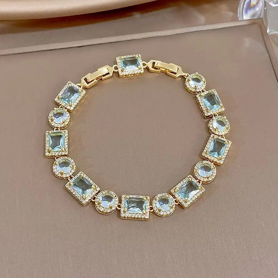 Gold-tone geometric link bracelet with blue square and round crystal stones, hinged clasp
