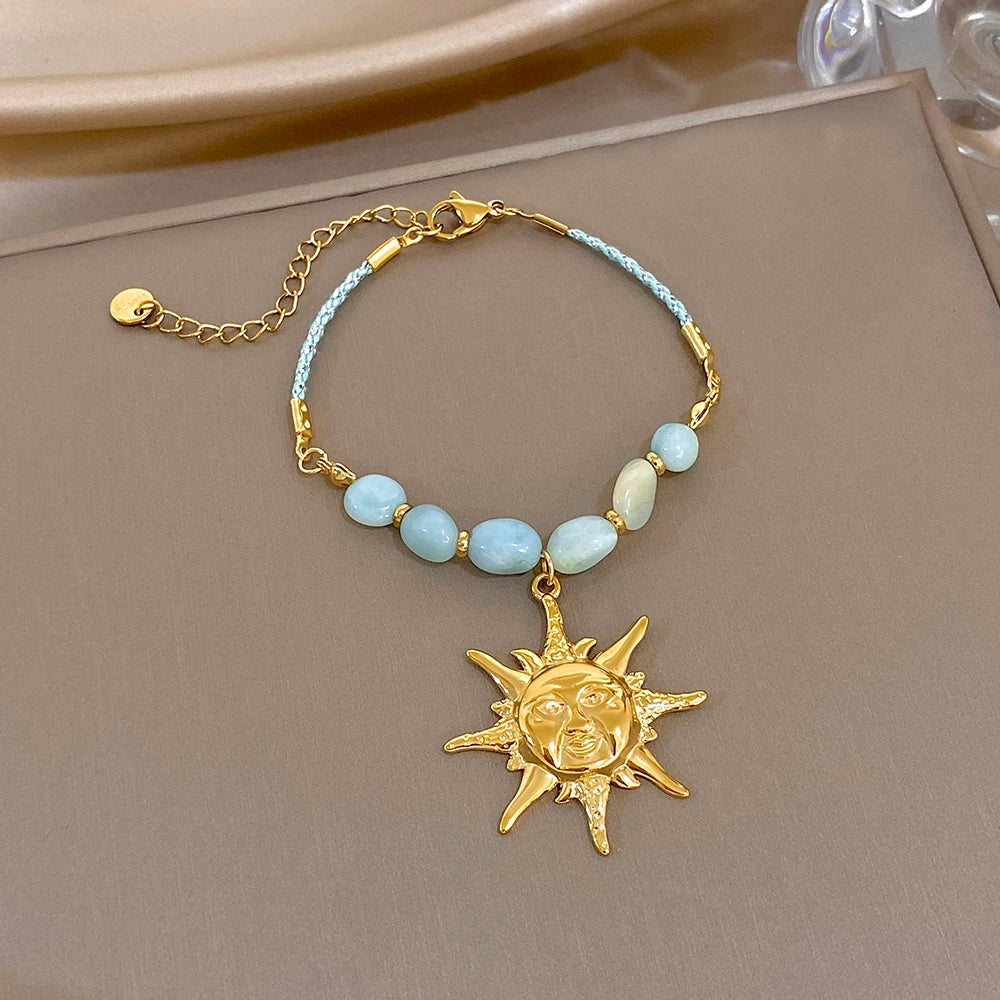 Light-blue beaded rope chain bracelet with blue beads and gold sun face charm pendant