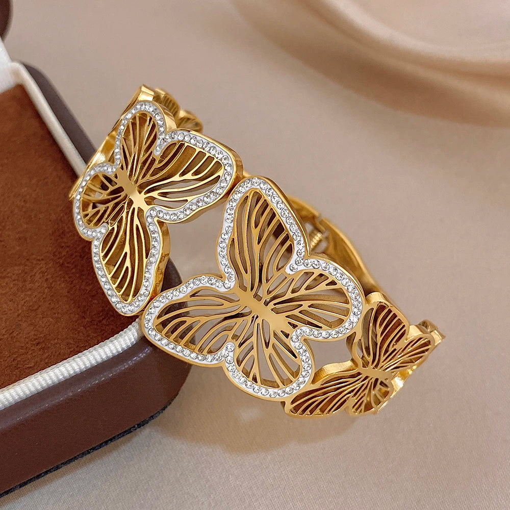 Gold-tone wide cuff bracelet with butterfly charms and sparkling rhinestone trim