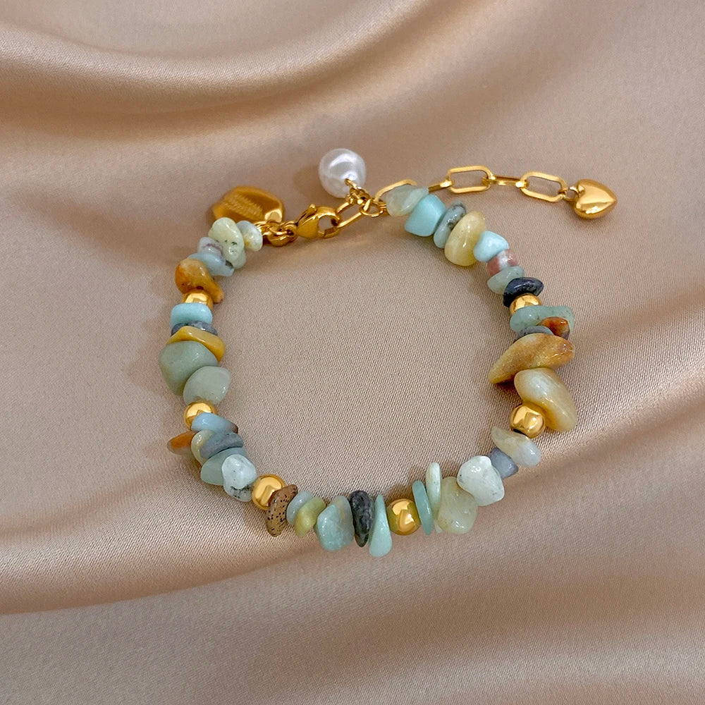 Adjustable gold chain bracelet with mixed irregular stones in pale blue, cream, and brown, pearl charm