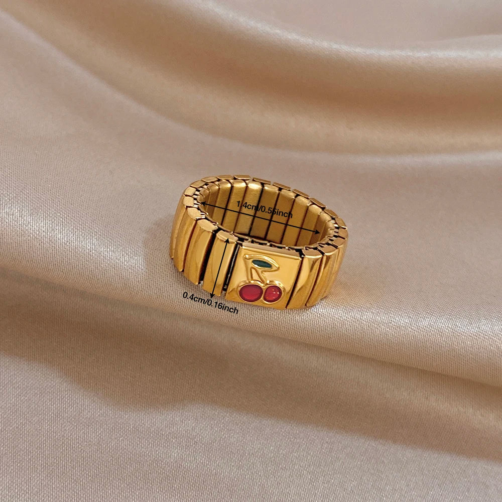 Gold adjustable watchband-style finger ring with red cherry enamel and green leaf accents