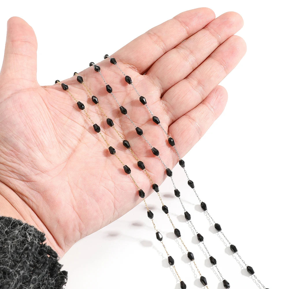 Black oval crystal bead chain held in hand, multiple strands with linked metal