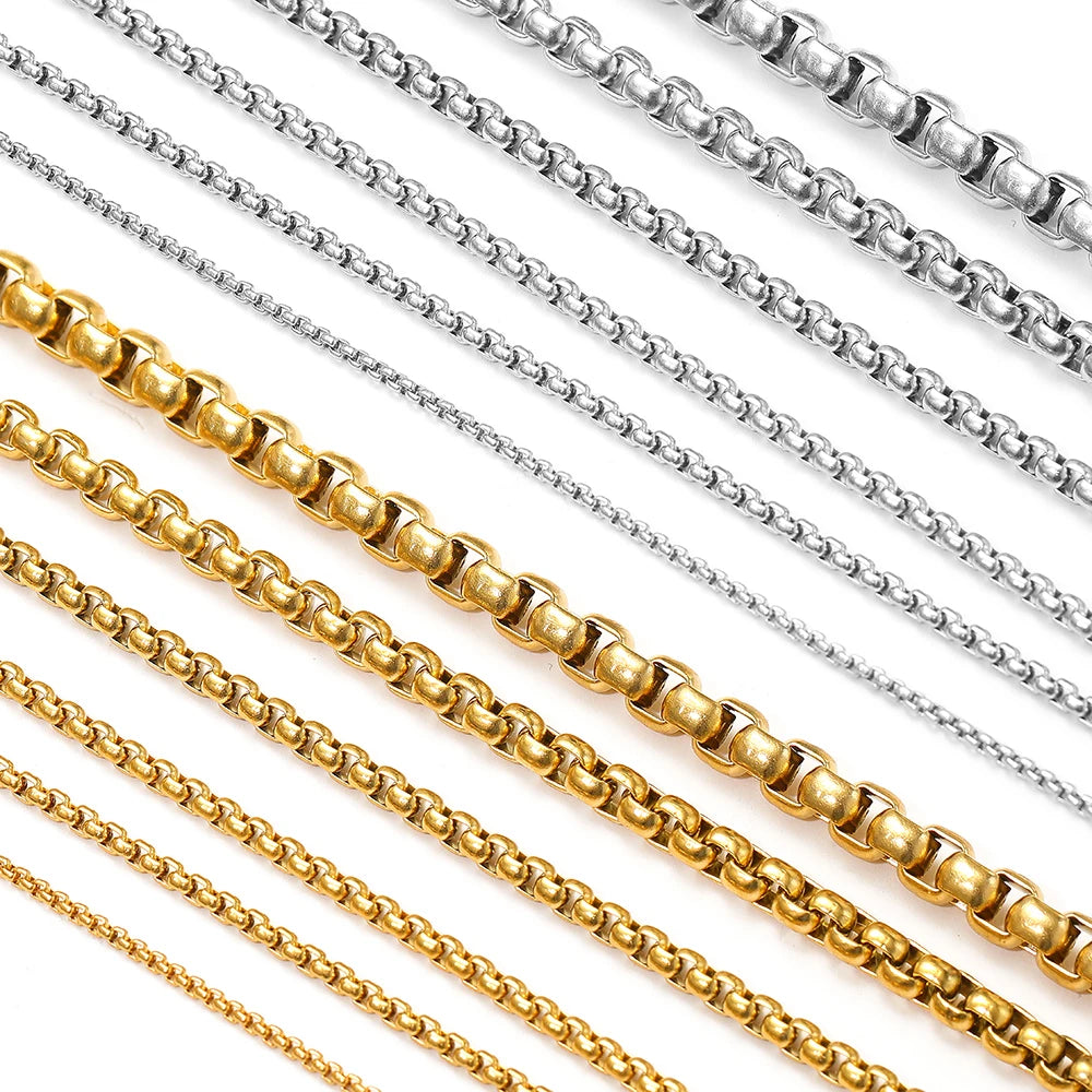 Rolo box chain strands in gold and silver, rectangular links on a flat surface