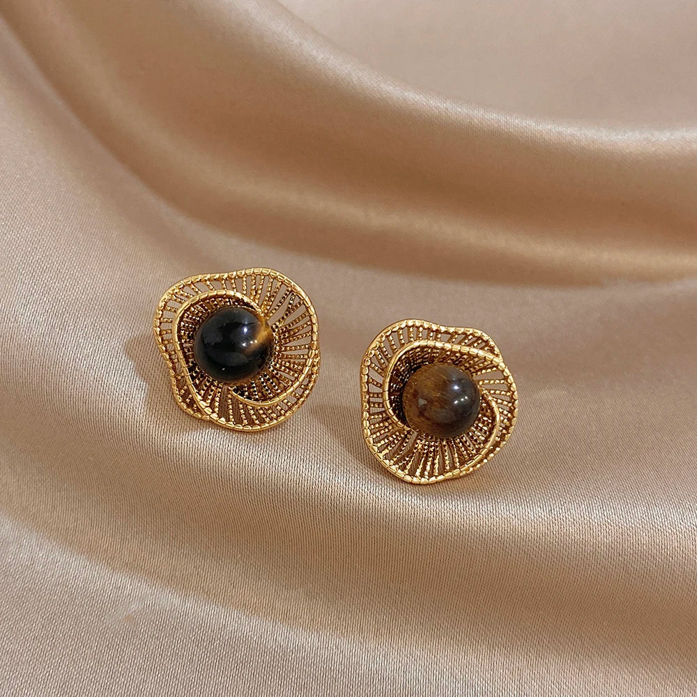 Gold-tone flower stud earrings with dark round beads and spiral filigree border
