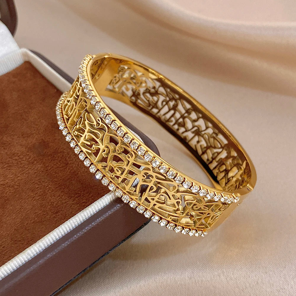 Gold-tone geometric bangle cuff with hollow engraving and rhinestone perimeter