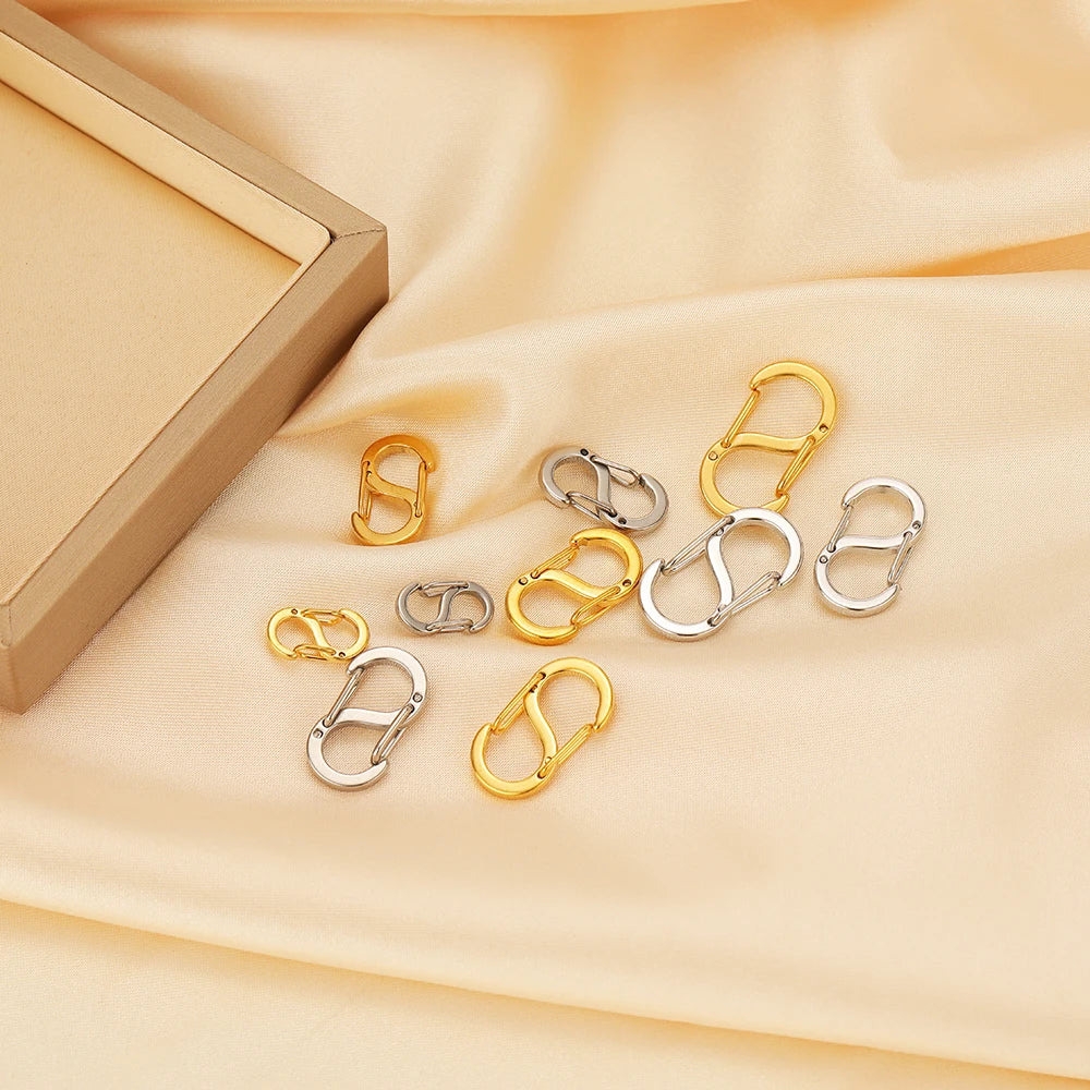 Letter S spring lobster clasps in gold and silver arranged on a light fabric