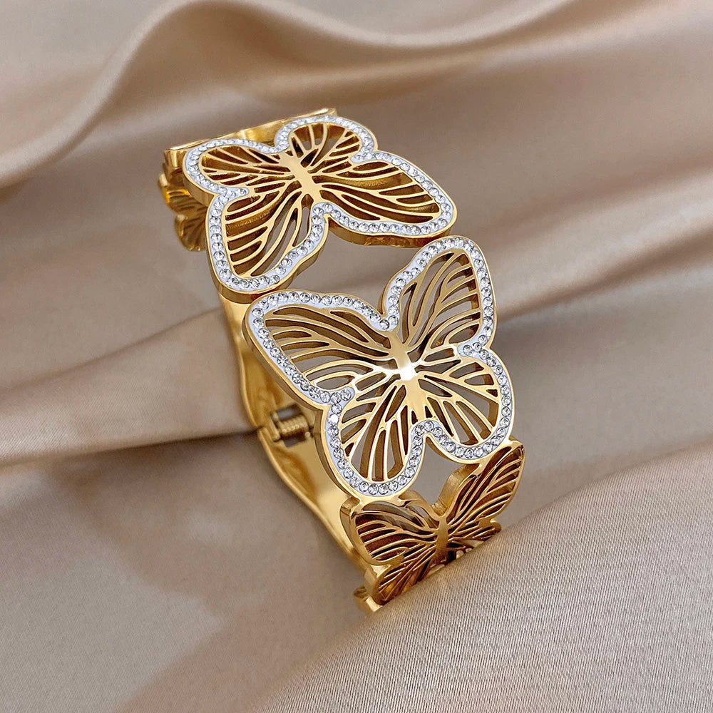 Gold-tone wide cuff bracelet with butterfly charms and clear rhinestone edging