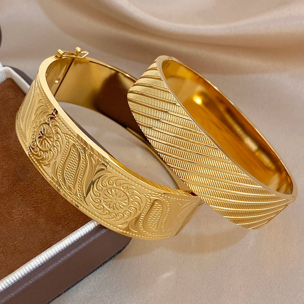 Gold-tone wide cuff bangles with carved floral medallions and textured ridges