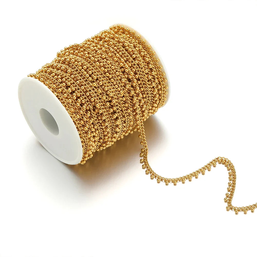 Gold beaded curb link chain on spool, with small ball drop chain strand