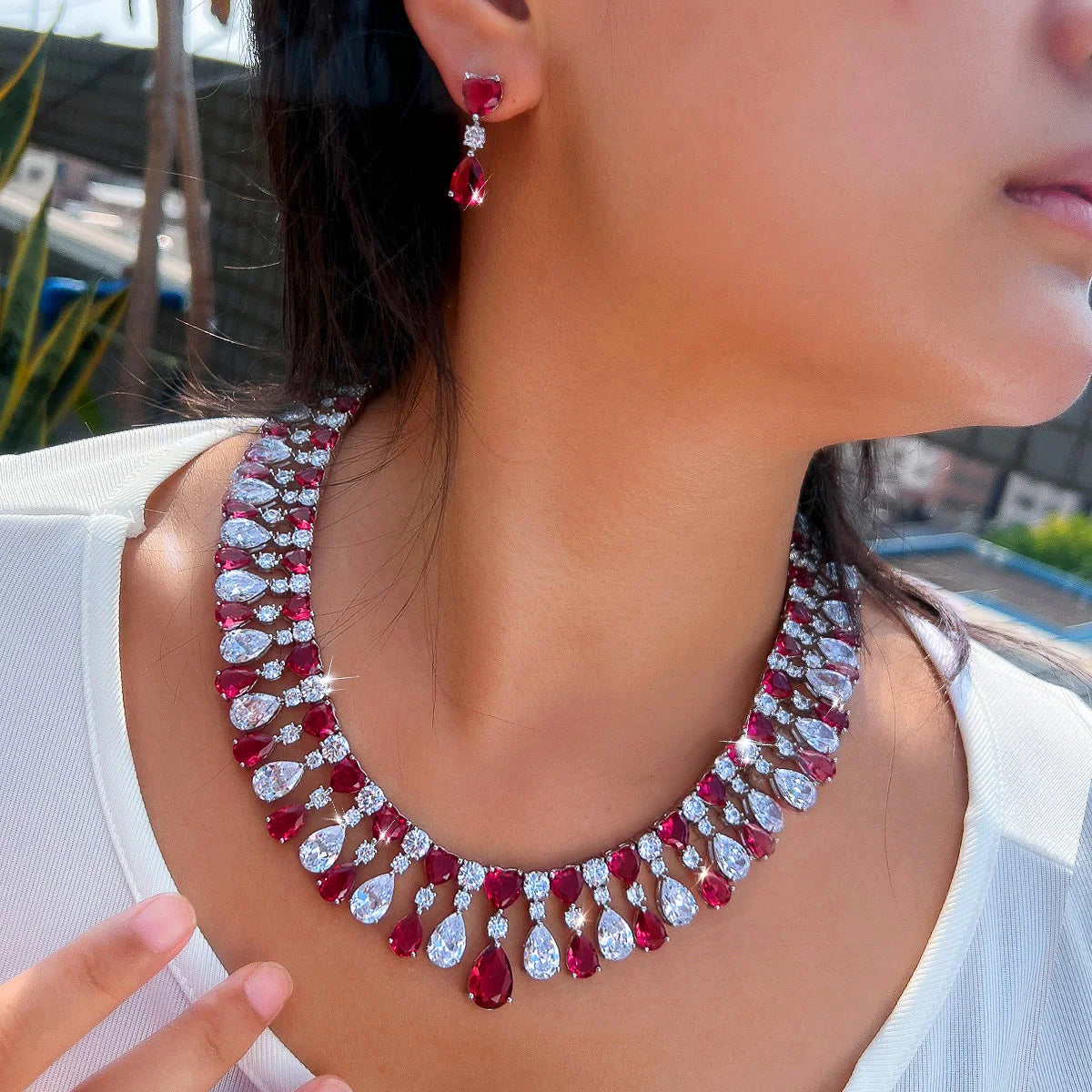 Red and clear teardrop rhinestone choker necklace with heart drop earrings, angled view