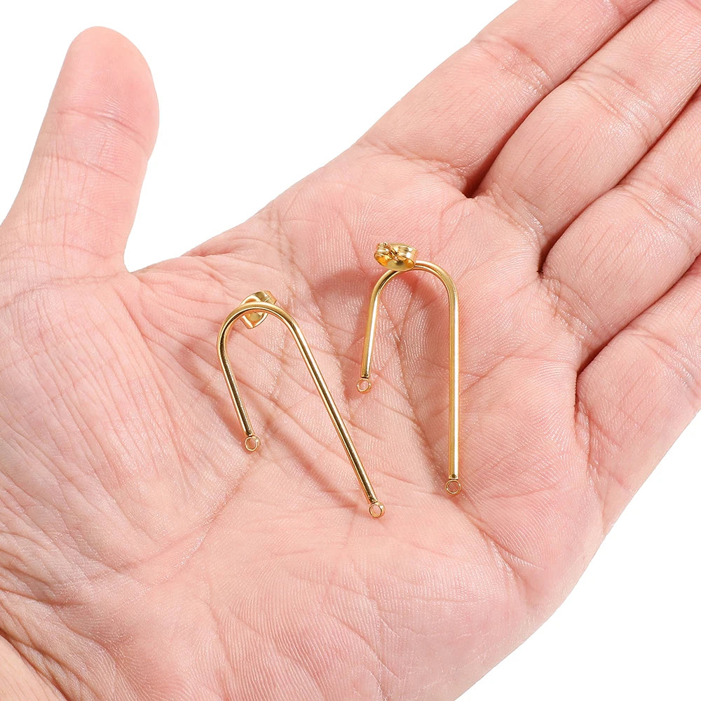 Gold long stick ear wire hooks connectors held in hand, two pairs visible