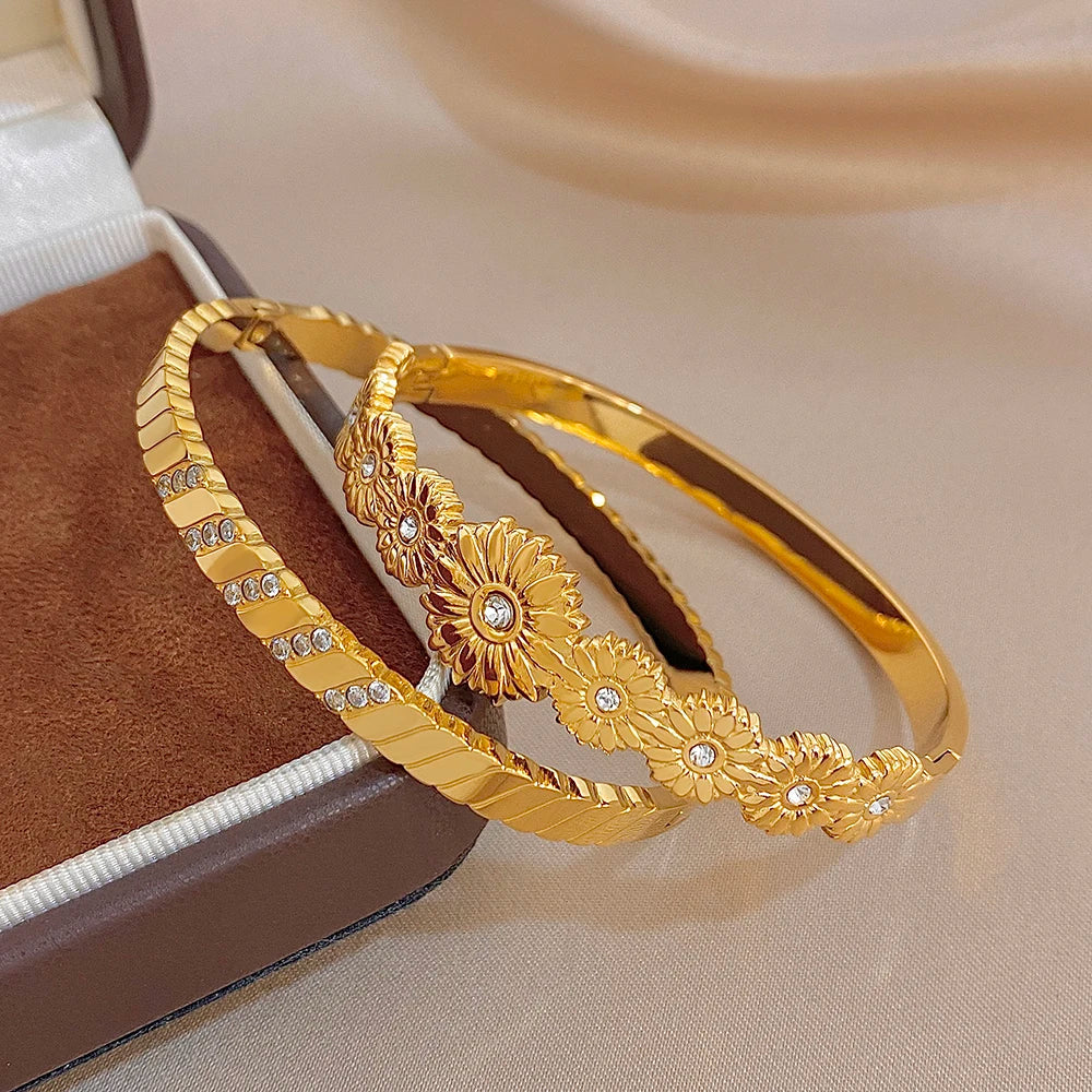 Gold tone bangles with ridged texture, floral medallions, and clear rhinestones