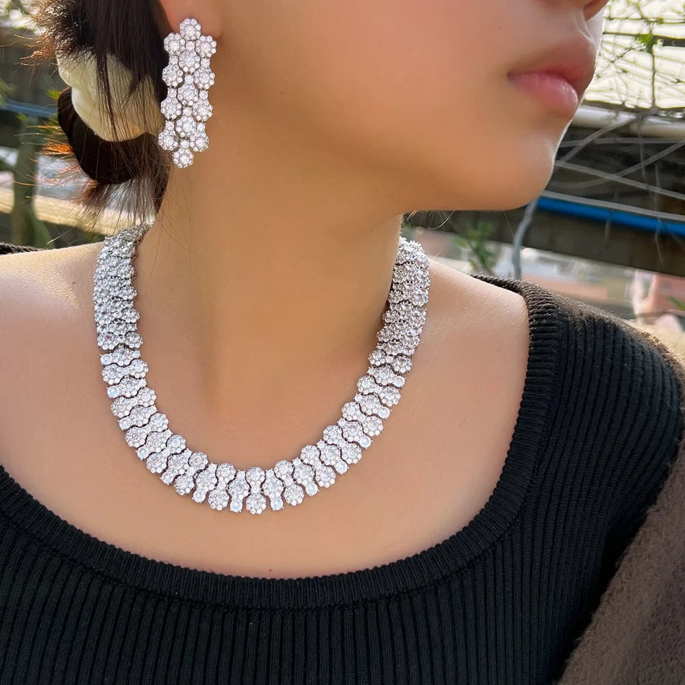 Silver-tone crystal necklace and matching flower-shaped earrings worn on a model