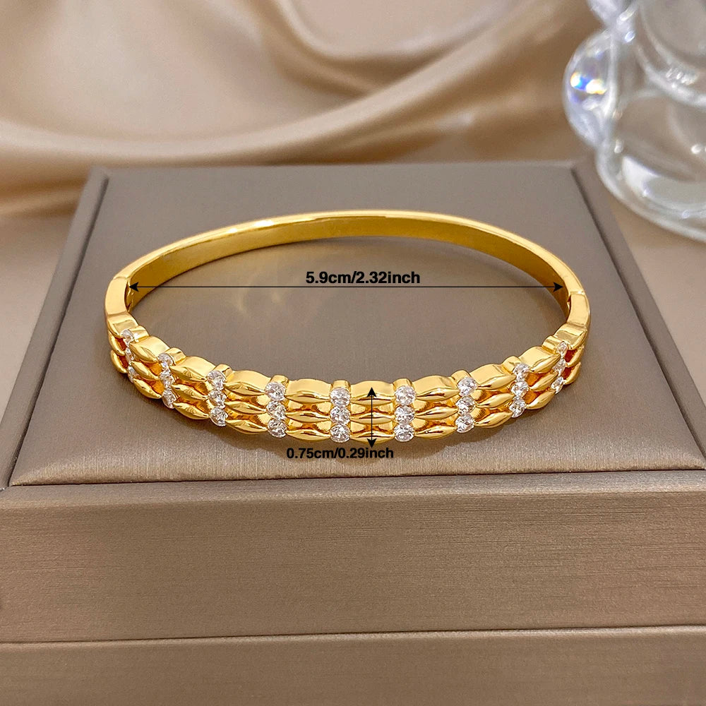 Wide gold-tone cuff bangle with textured link pattern and round crystal stones