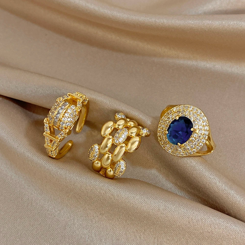 Gold-tone open geometric zircon ring with blue oval center stone and crystal halo