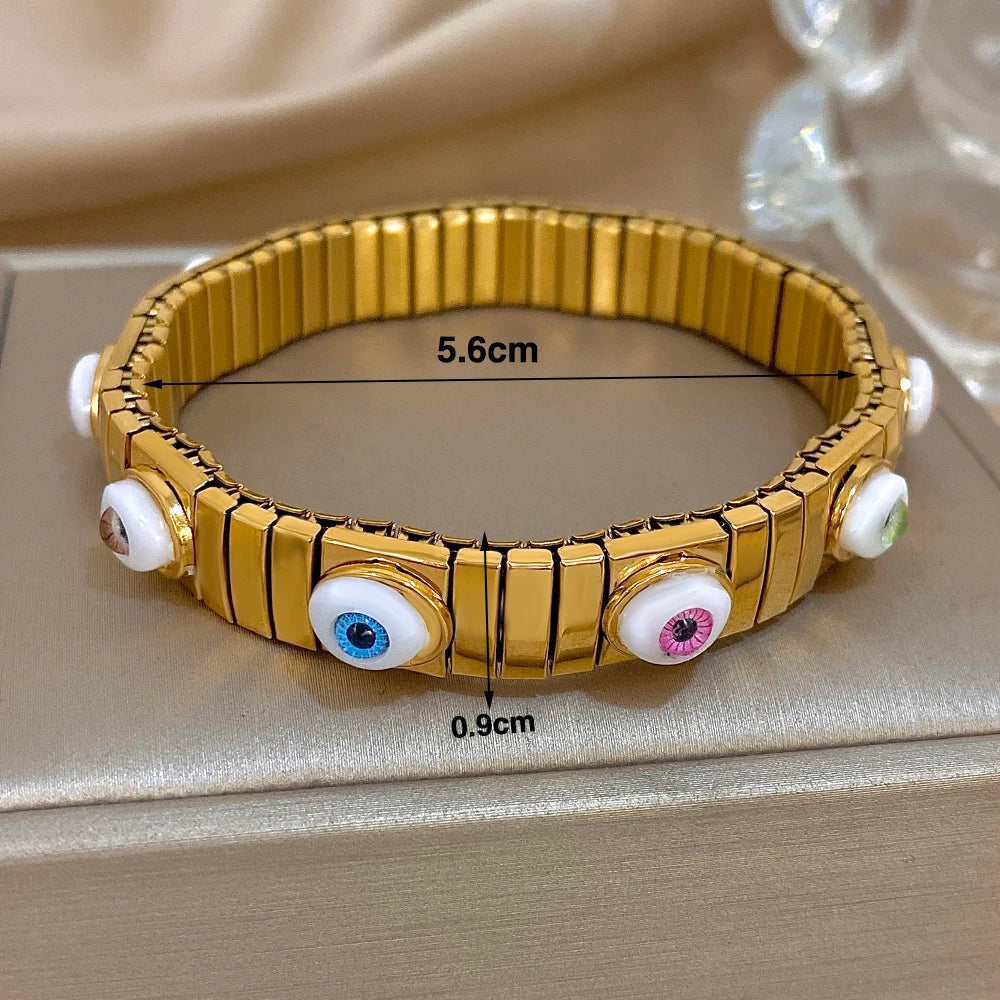 Gold-tone evil eye bracelet with glossy oval eye insets on an elastic watchband style