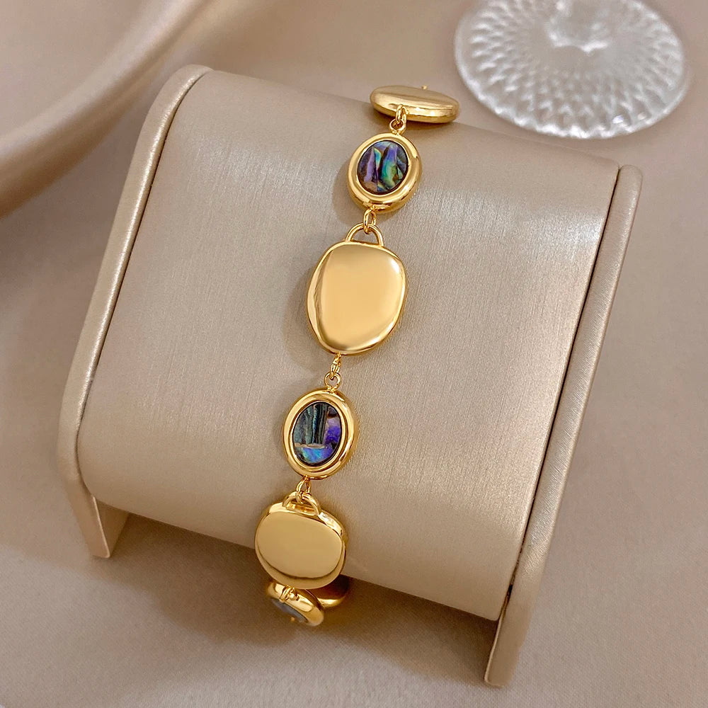 Gold-tone bracelet with oval disc links and iridescent abalone shell drop-bead detail