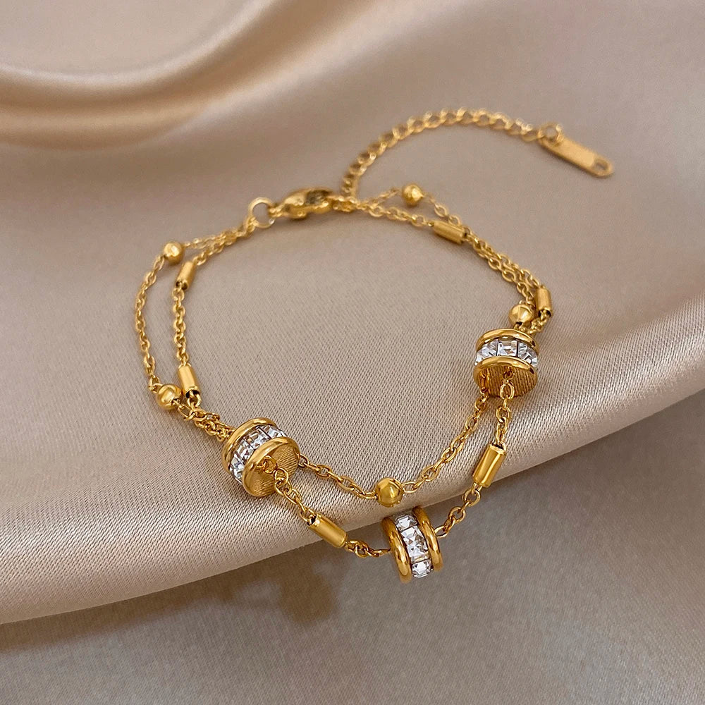 Gold double-layer chain bracelet with rhinestone bead cylinders and lobster clasp.
