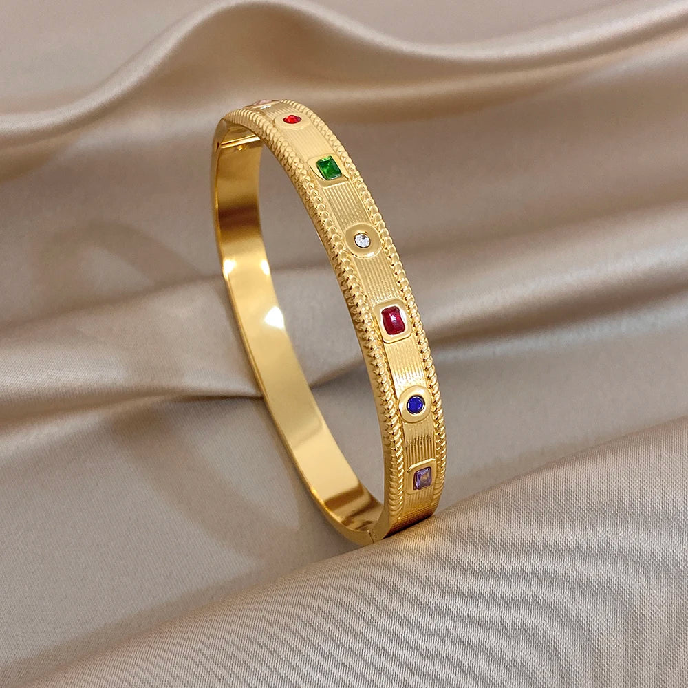 Gold-tone cuff bangle with multicolor gemstone insets and small clear rhinestones