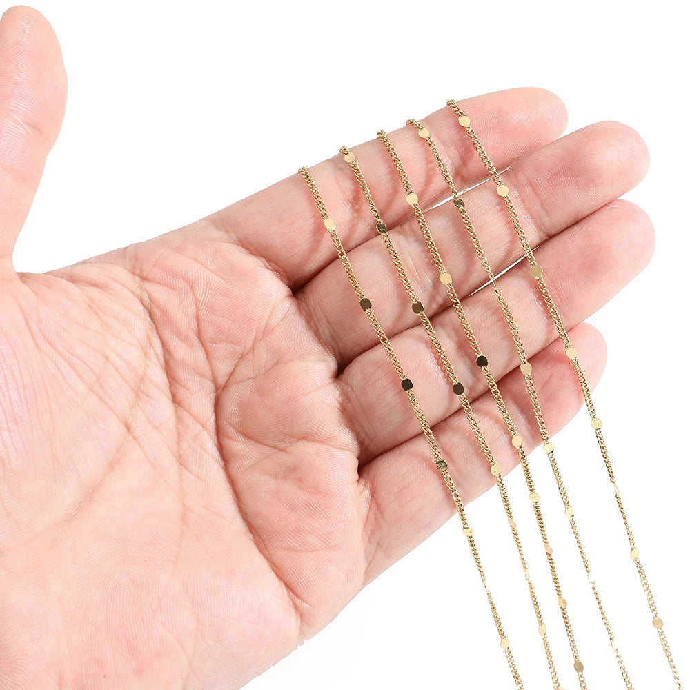 Gold textured flat oval chain draped over fingers, thin glittery link centers