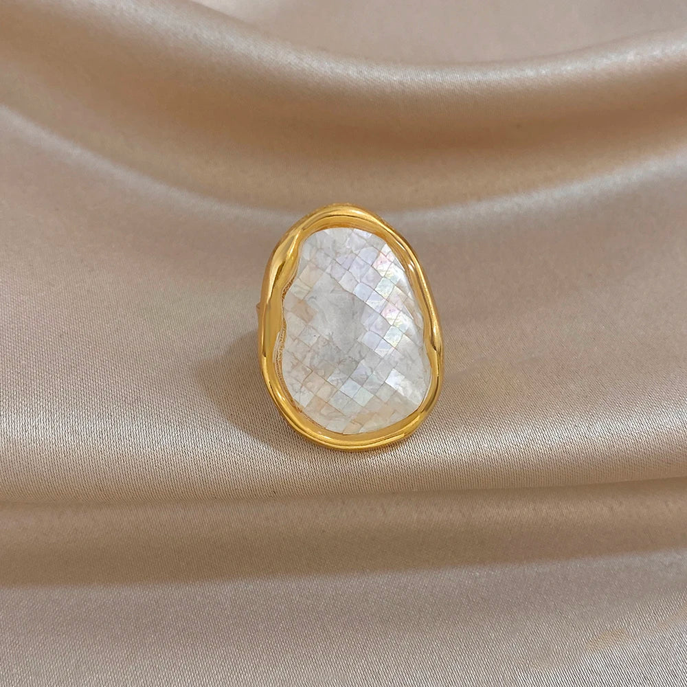 Gold-plated abalone shell ring with white iridescent oval stone, scalloped golden frame