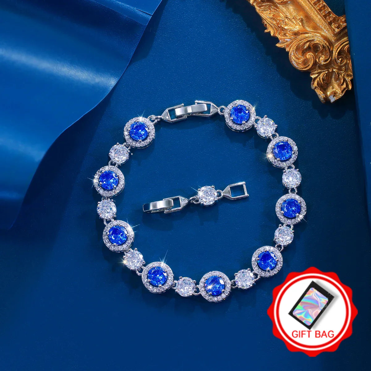 Silver-tone tennis bracelet with round blue stones, clear accents, and a gift bag