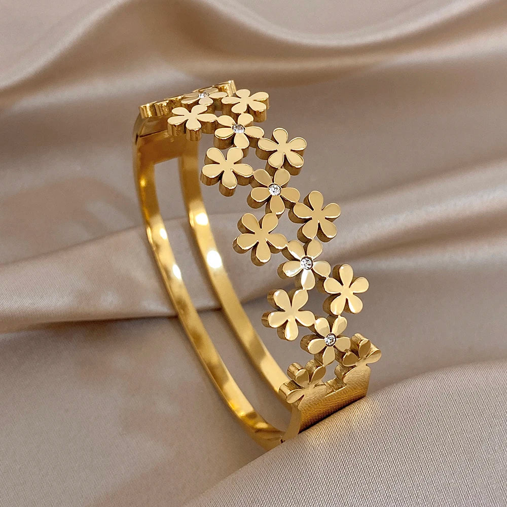 Gold-plated wide bangle with layered flower charms and small crystal accents