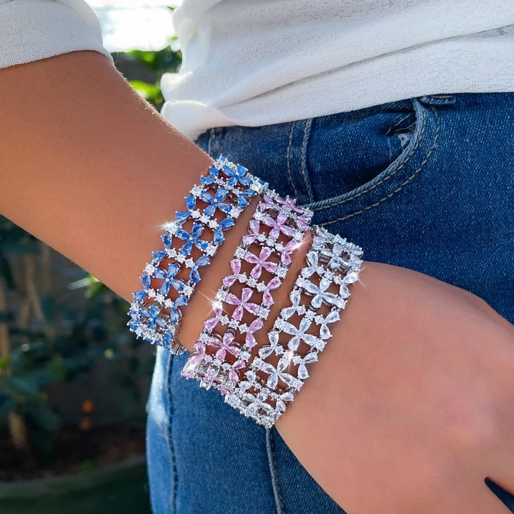 Wide floral crystal tennis bracelet set in blue, pink, and clear stones, worn on a wrist