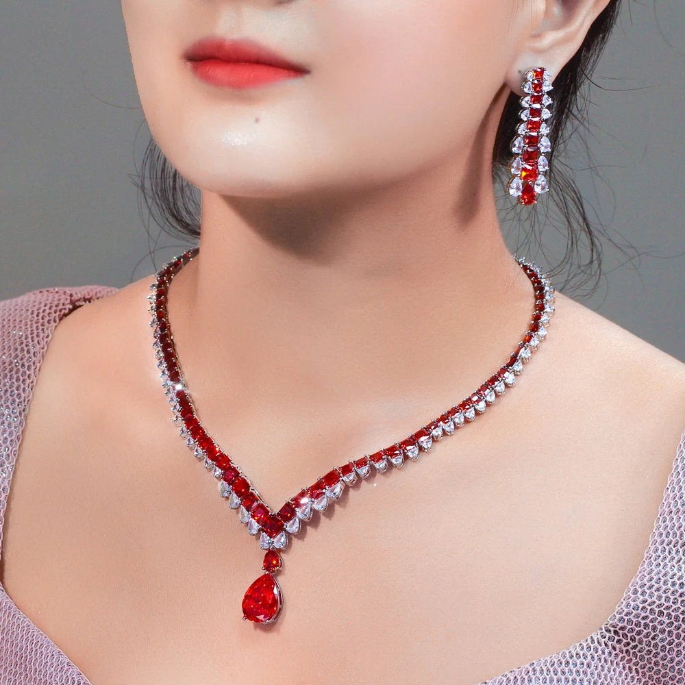 Red and clear cubic zirconia jewelry set worn, with a V necklace and long drop earrings