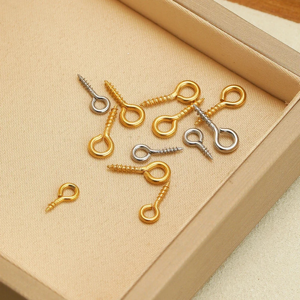 Assorted gold and silver screw eye pins with threaded shafts and looped eye hooks