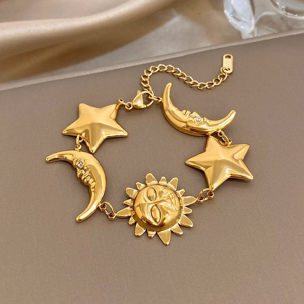 Gold-tone charm bracelet with crescent moons, star charms, and a sun medallion centerpiece