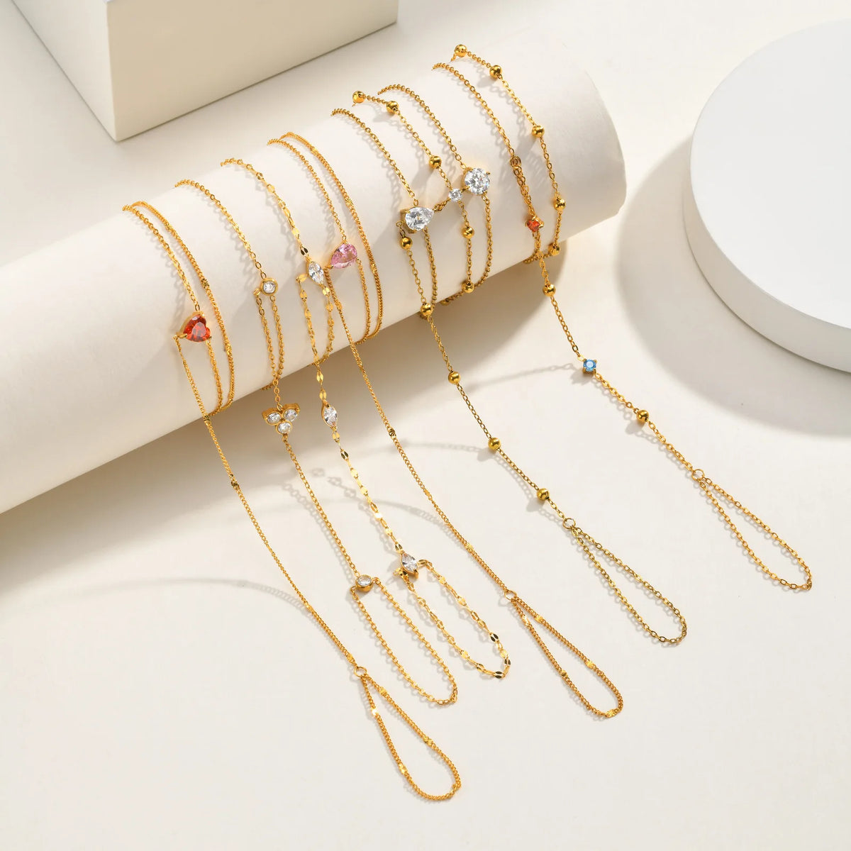 Gold-tone layered heart CZ hand chain bracelets displayed in rows