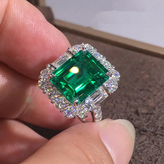 Square-cut green cubic zirconia halo ring with silver-toned band and baguette stones