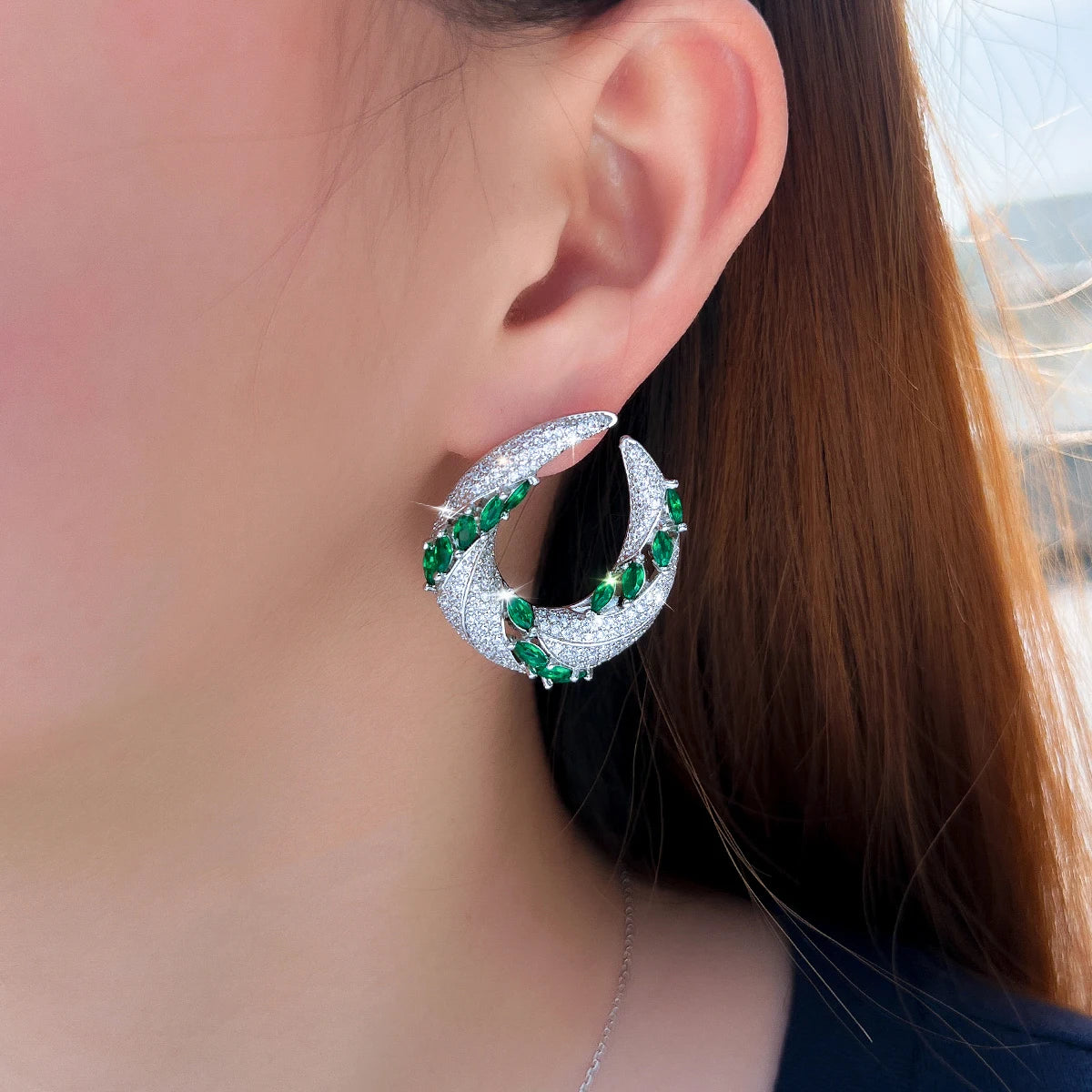Crescent earring with green and white stones worn on the ear