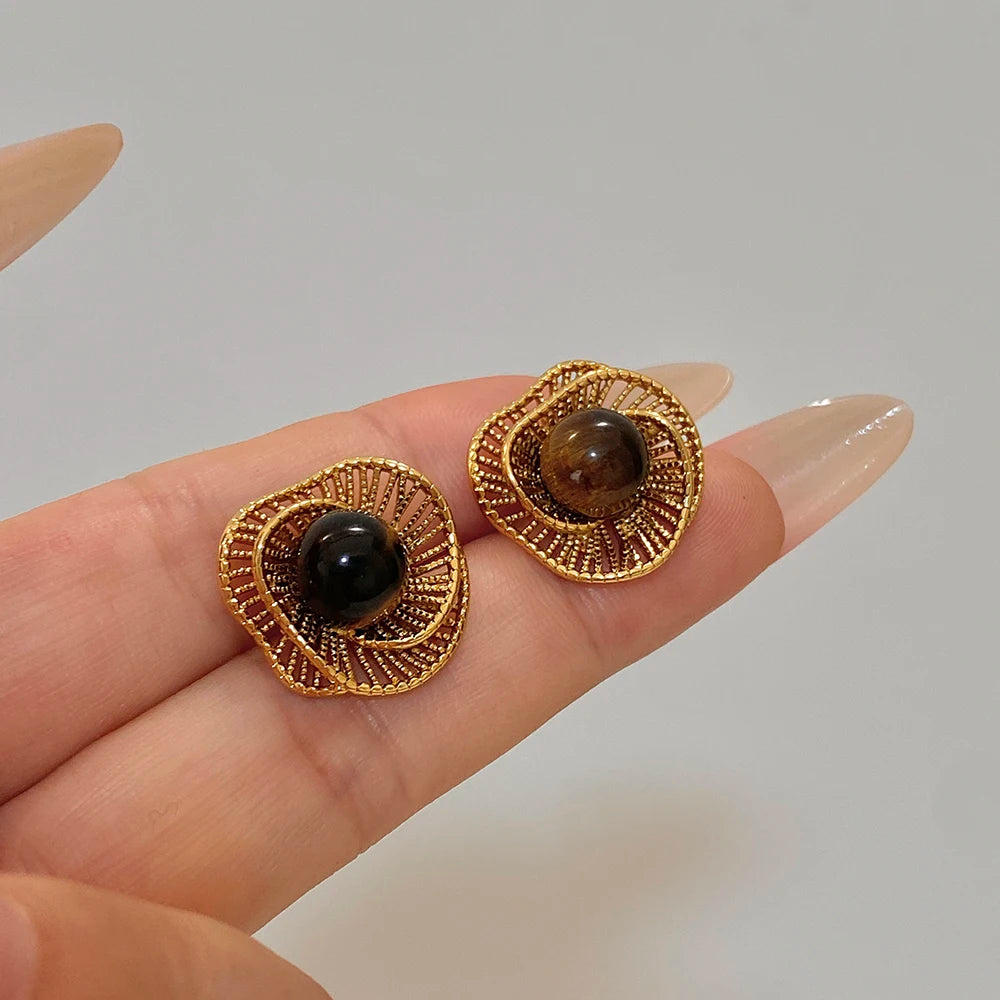 Gold-tone flower stud earrings with dark round bead on gold textured setting
