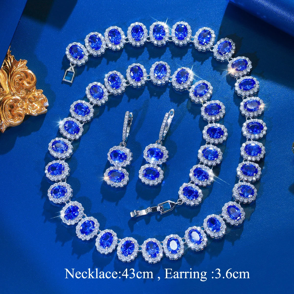 Royal blue cubic zirconia jewelry set laid out: necklace with blue stones and drop hoop earrings