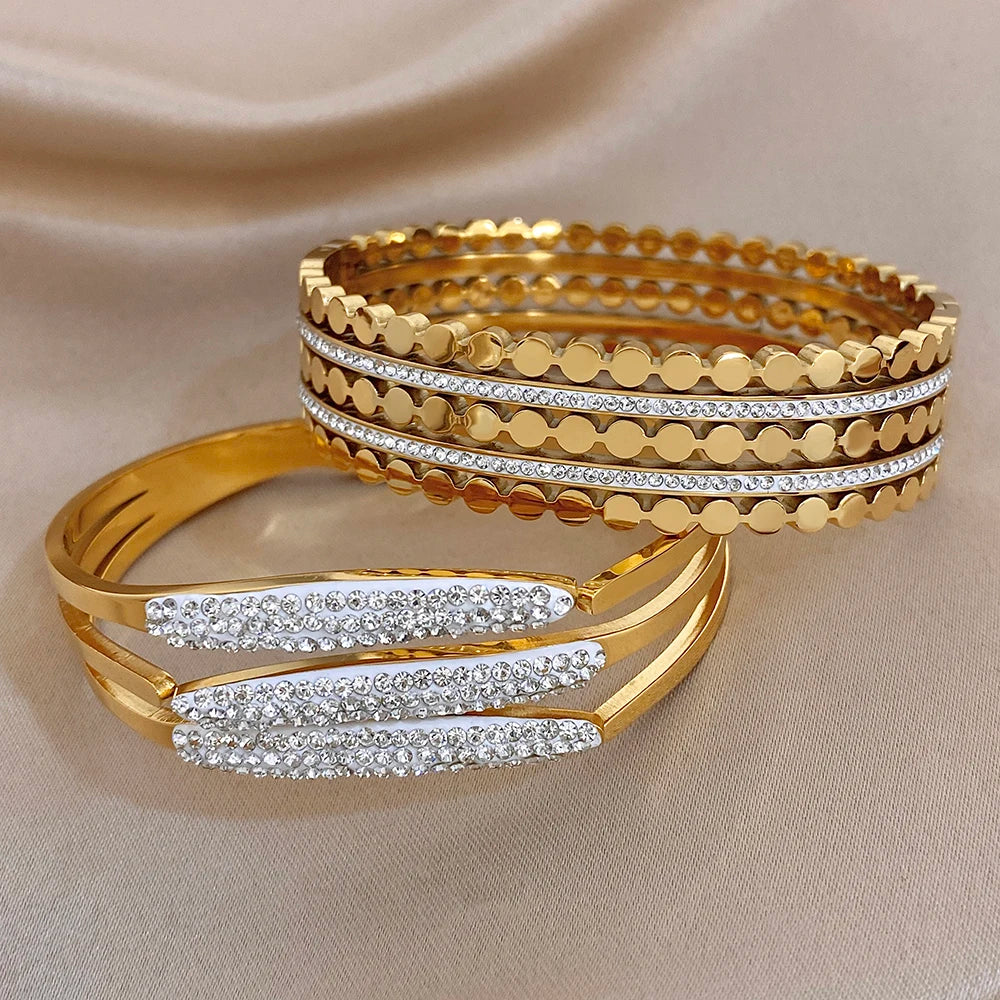 Gold-tone wide cuff bangles with textured scalloped edges and rhinestone center striping