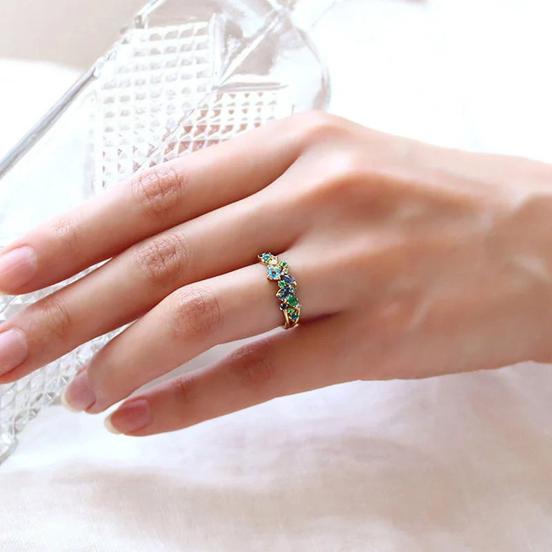 Gold-tone multicolor cubic zirconia ring with small blue and green stones on hand