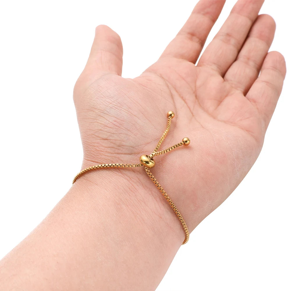 Gold box chain bracelet connector on open palm, featuring round bead end caps