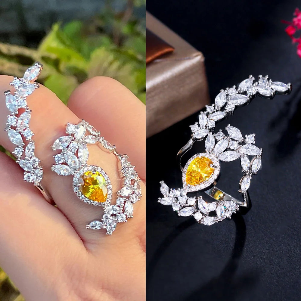 Open ring with a yellow oval stone framed by clear stones in a leafy design