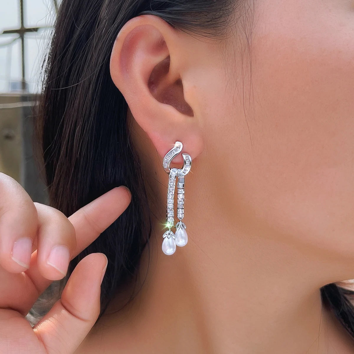 Silver-tone zirconia earring with two pearl drops, shown worn on the ear.