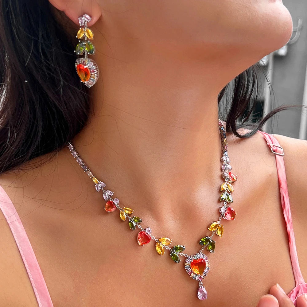Multicolor heart zircon necklace and drop earring worn, showing colorful stones and pink pendant