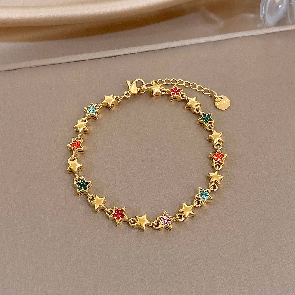 Gold-tone star charm bracelet with green, red, and blue gem star details