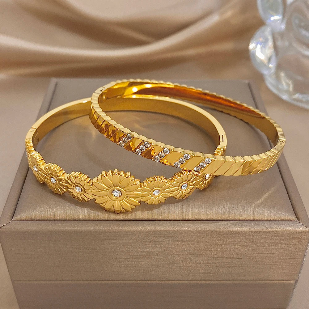 Stackable gold tone bangles with floral centerpiece and clear rhinestone insets