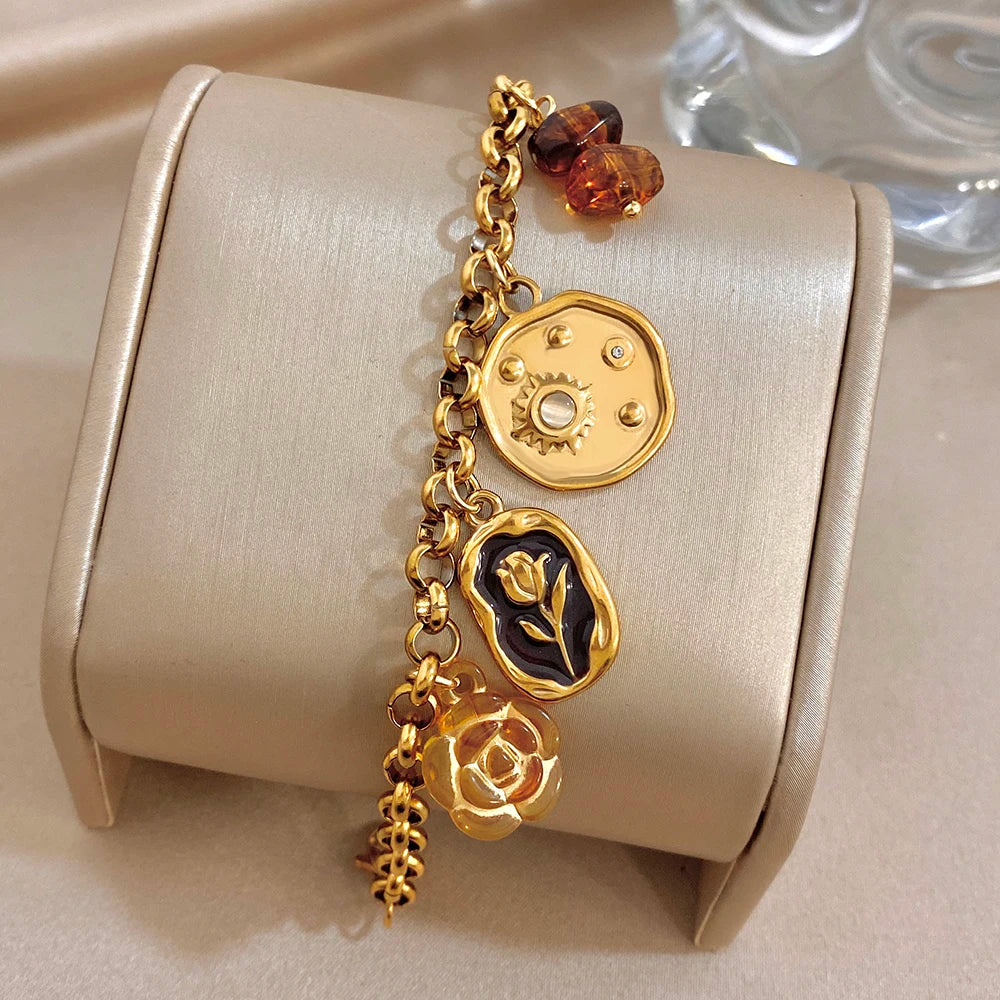 Gold charm bracelet on roll with heart, coin charm, rose and amber beads