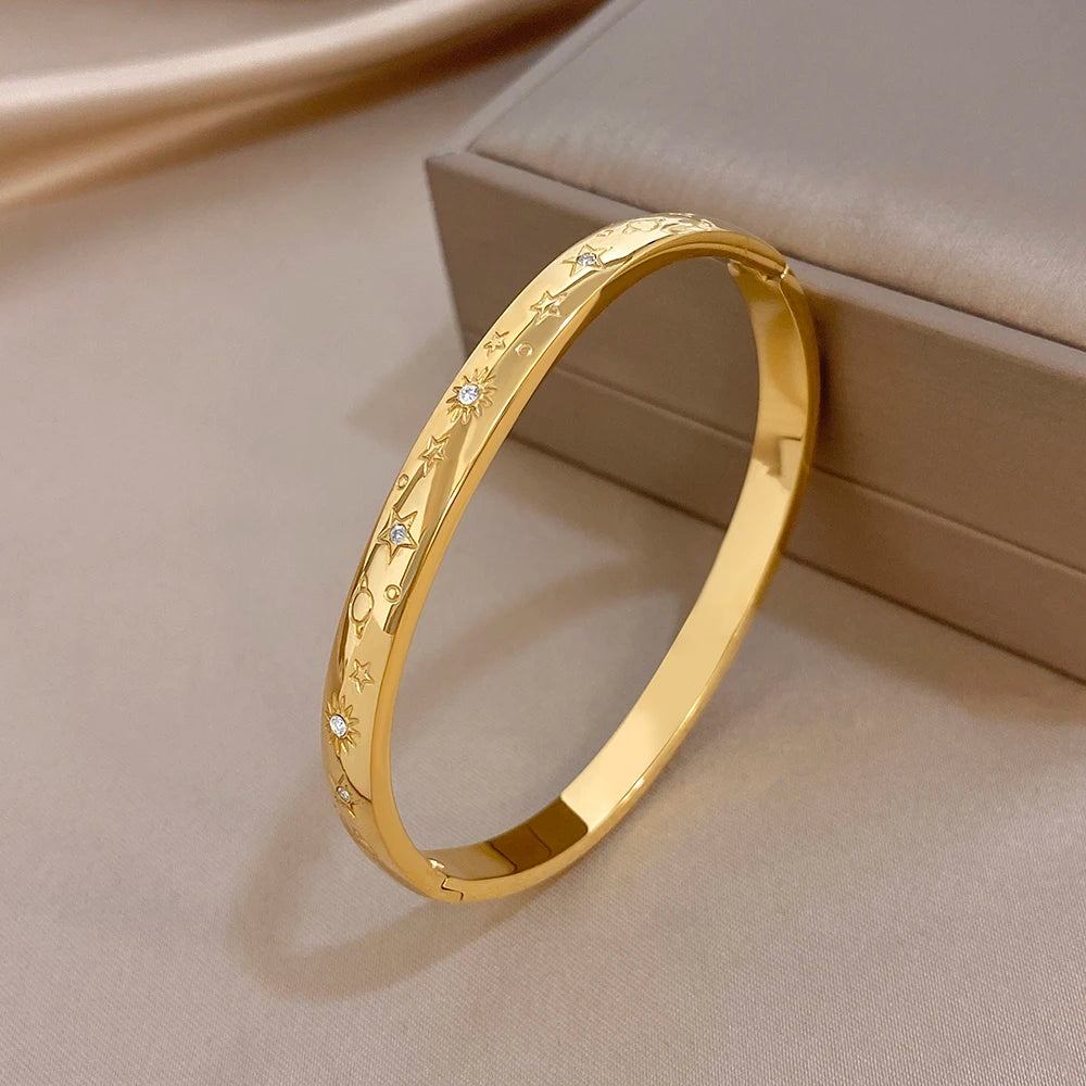 Gold-tone wide cuff bracelet with engraved stars and small crystal-like stones