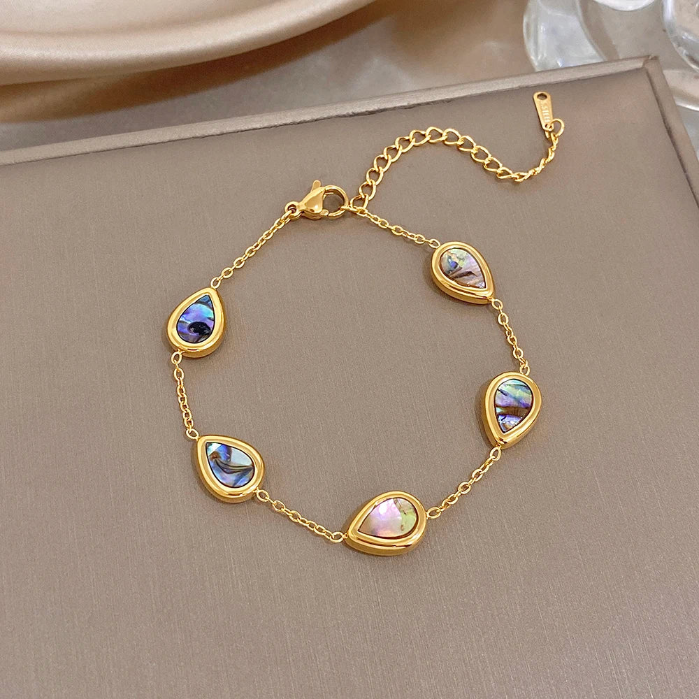 Gold plated oval charm bracelet with iridescent abalone discs and blue highlights