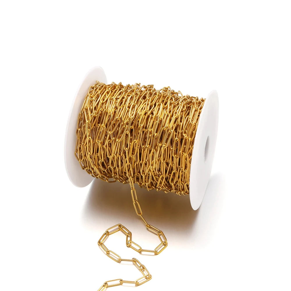 Gold-tone oval flat cable chain on a spool, cross/paperclip style links